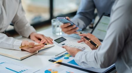 financial asian advisor showing plan of investment to clients in the consultancy office.